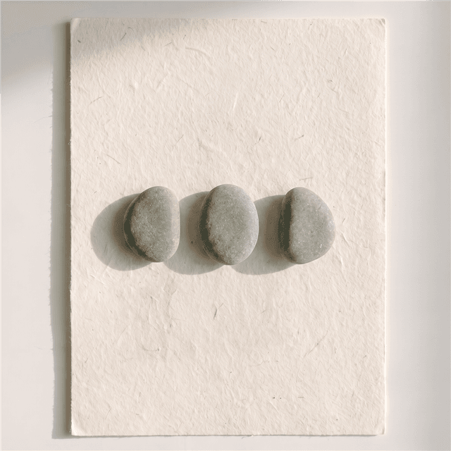 Three smooth river stones arranged in a line on warm paper, Devon Okafor's mark